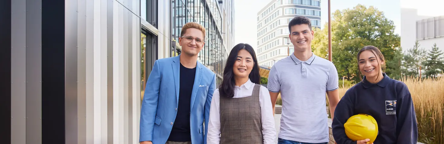 Vier Auszubildende stehen auf dem EUREF Campus nebeneinander