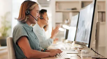 Eine Frau sitzt am Computer und telefoniert mit einem Headset